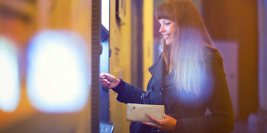 A young woman is using her Debit Card at an ATM