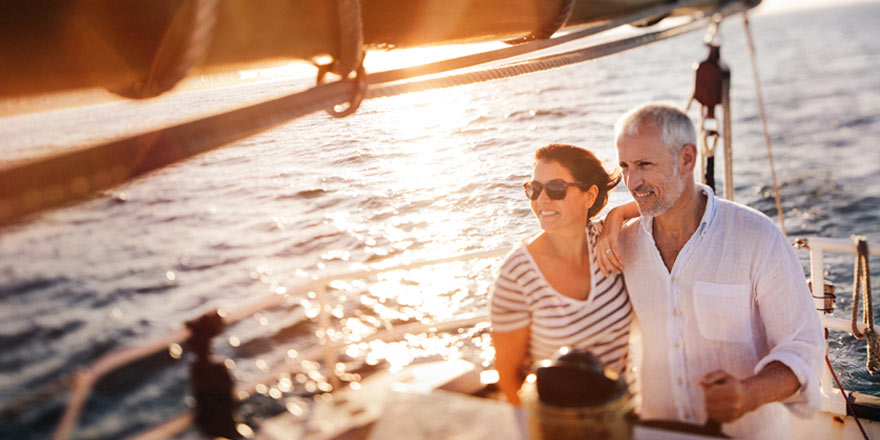 A happy middle-aged couple who opened a Diamond Savings account are sailing while looking towards the horizon