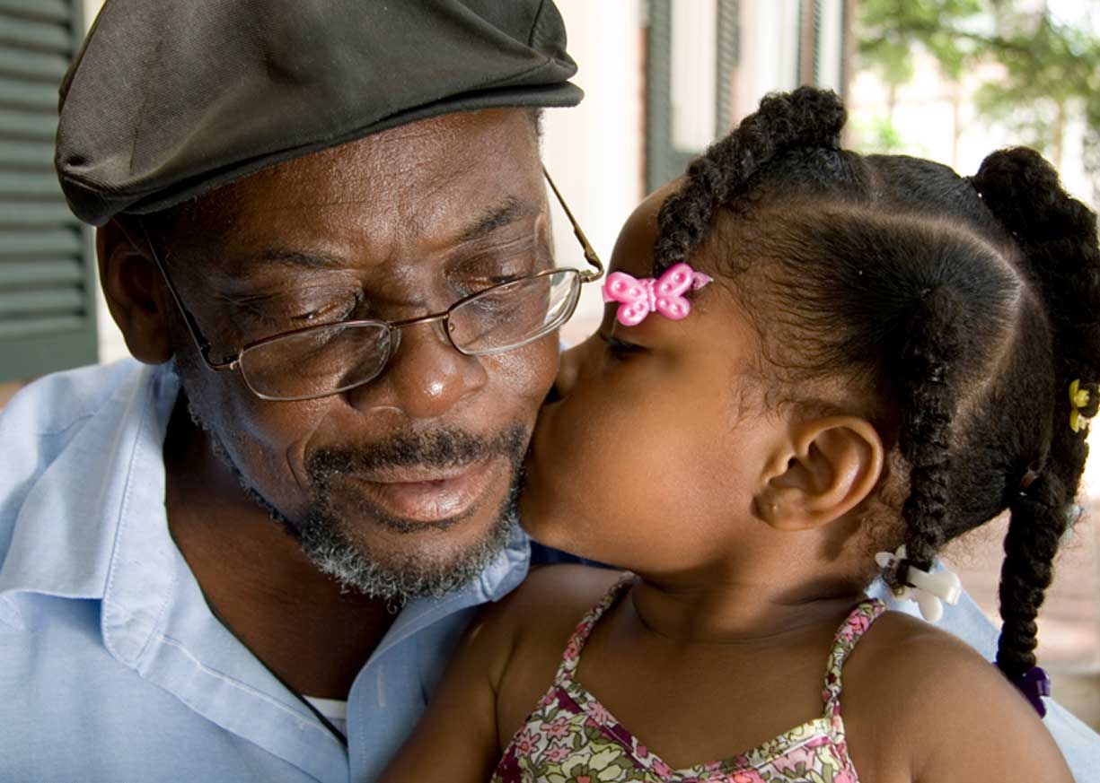 Elderly gentleman being kissed on the cheek by his granddaughter planned for retirement savings with an IRA Money Market