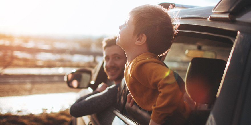 A happy father who received an Express Personal Loan and his young son enjoy a view of the ocean from their SUV