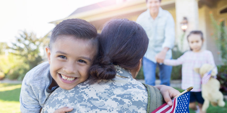 A U.S. Military family who received assistance via the Servicemembers Civil Relief Act embrace in front of their home 