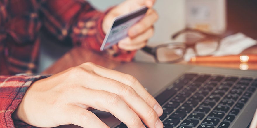 A man on a laptop is holding a debit card and researching ways to protect his personal information and account security