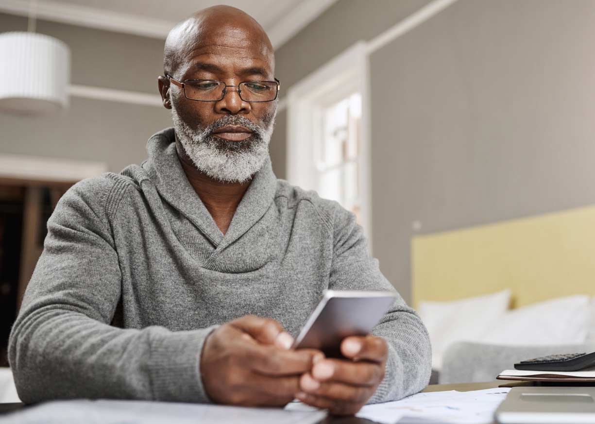 An older gentleman is using his phone to log in to online banking and the mobile banking app