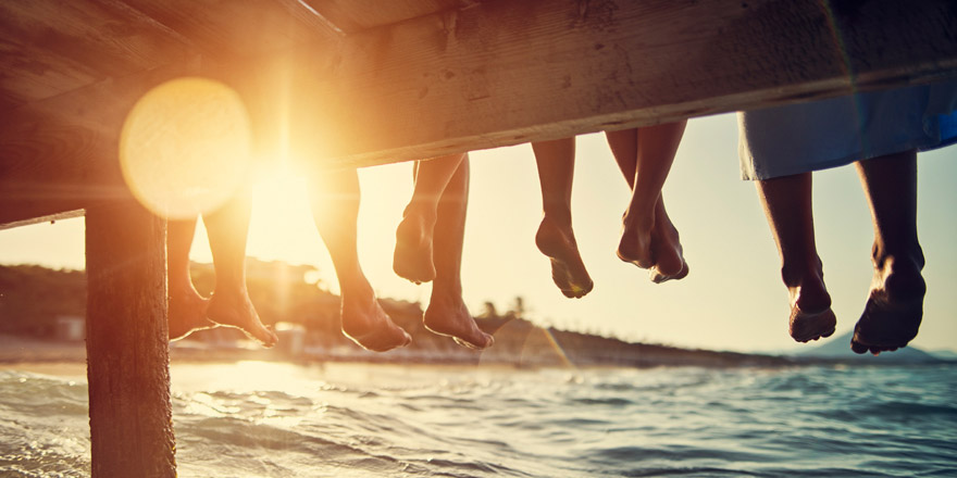 A group of friends who have overdraft services relax and dangle their legs on the edge of a pier