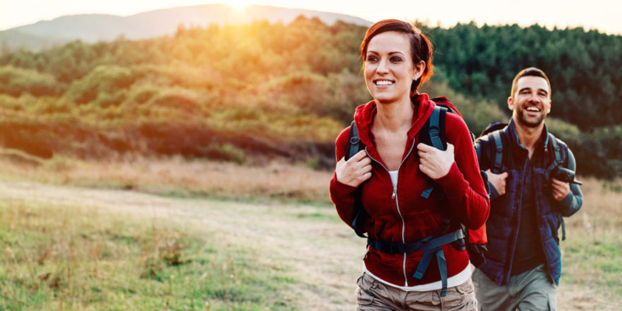 Younger couple who are saving money in a Money Market account are backpacking on a hiking trail