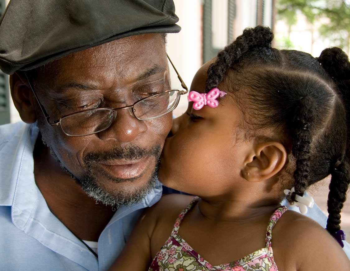 Elderly gentleman who is being kissed on the cheek by his granddaughter saved money for retirement in an IRA