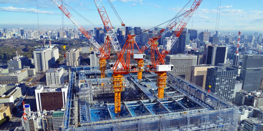 A series of cranes works to construct a large building project that was financed with a commercial real estate loan