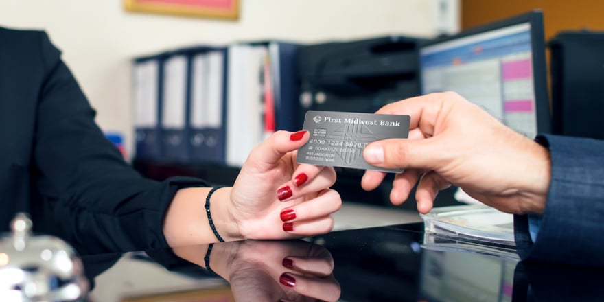 Close up of a banker handing a customer a new Commercial Credit Card from First Midwest Bank