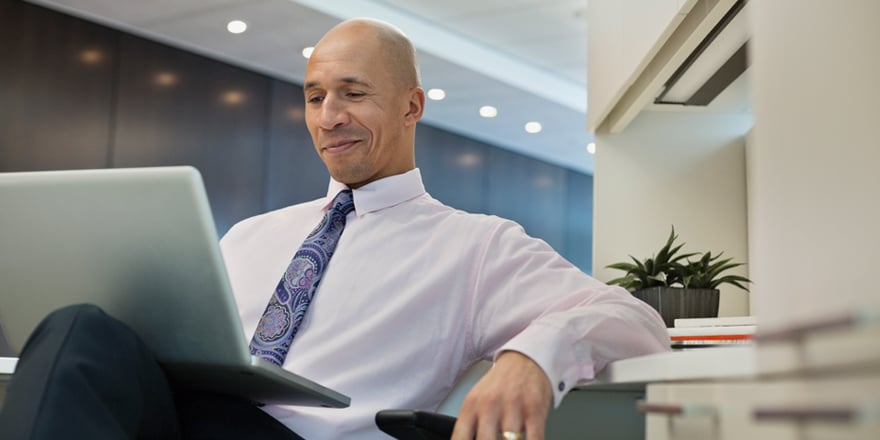 A businessman confidently looks at his laptop and watches videos on business online banking services