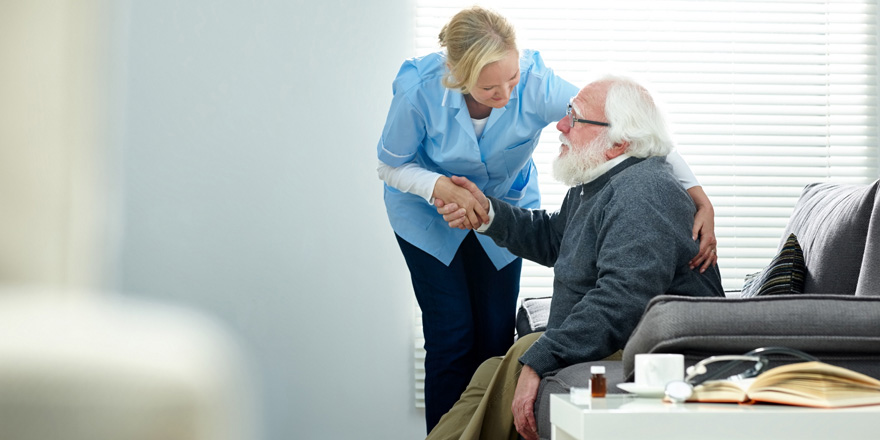 A healthcare professional assists a senior citizen in a facility that received a loan through the healthcare finance program