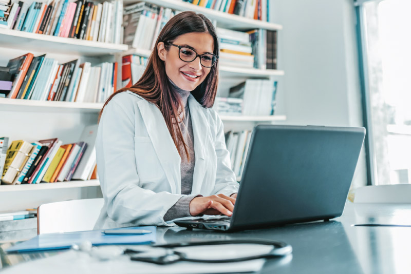 A doctor taking notes on her laptop