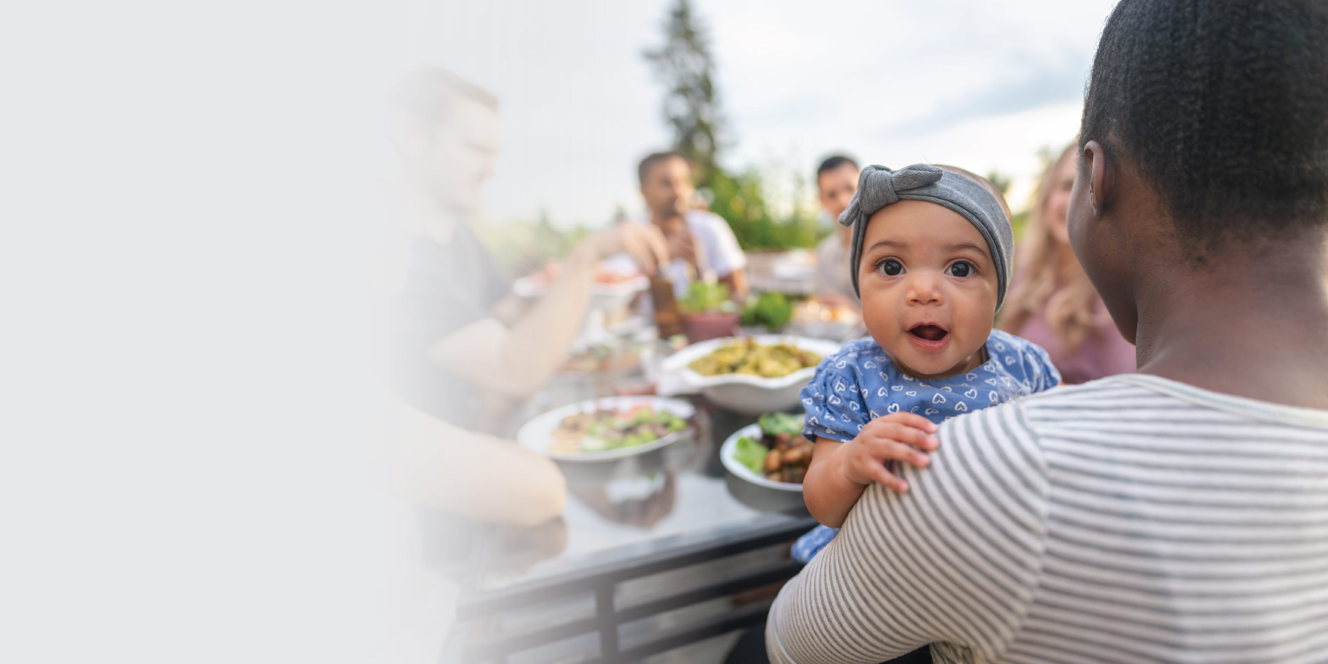 A family of Midwest Checking customers enjoying a picnic and holding a happy baby