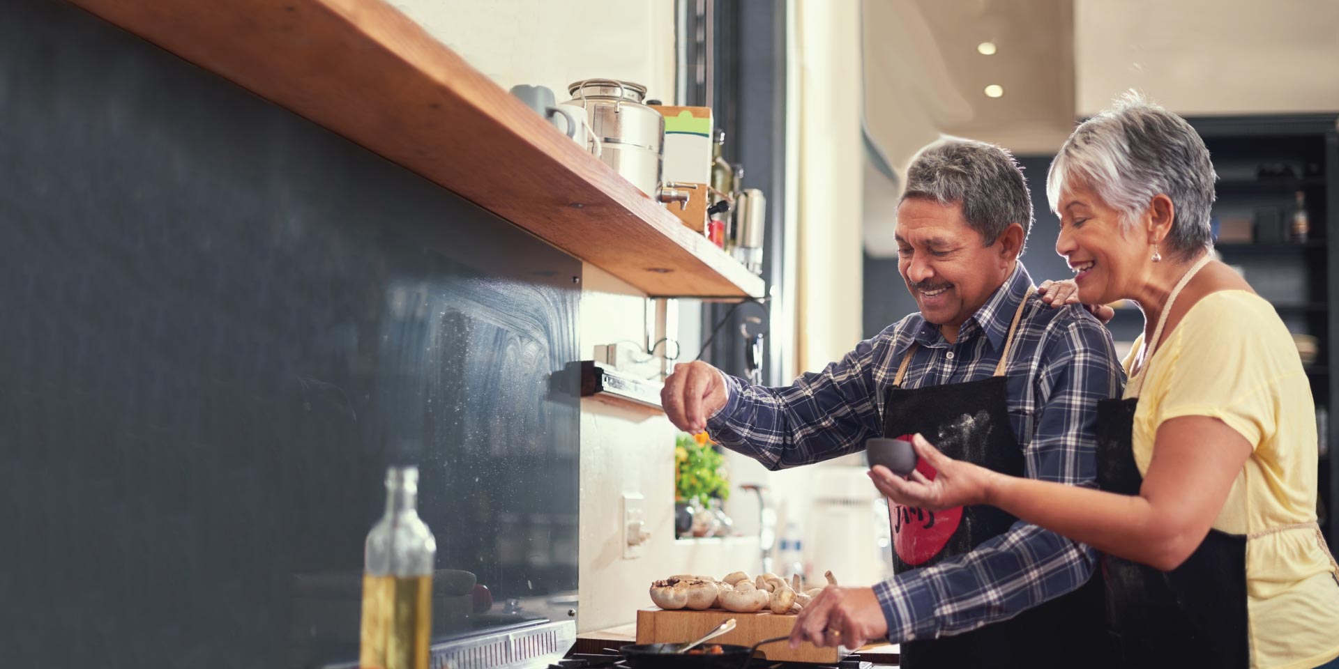 A happy couple who have a Diamond Checking account cooking together in a kitchen