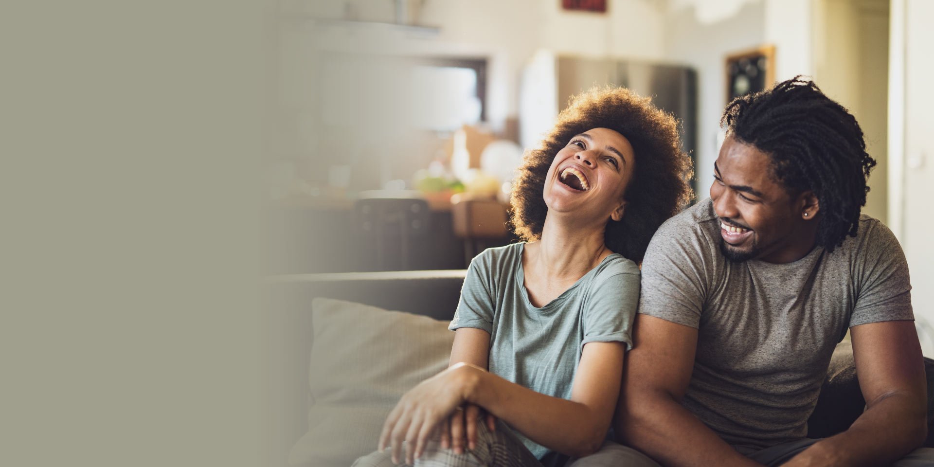 A happy Easy Checking account couple talking together on a couch and laughing