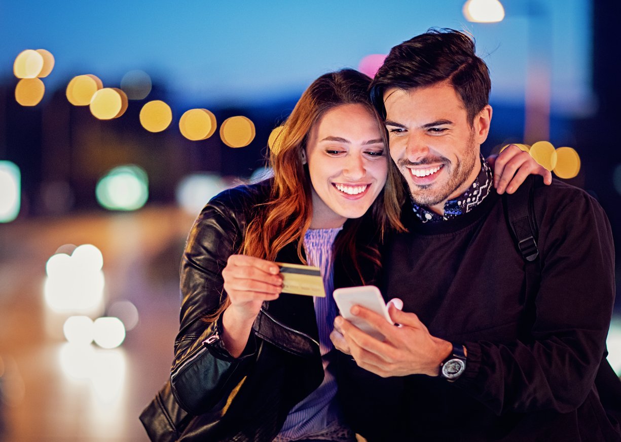 A young couple looking at his mobile device.