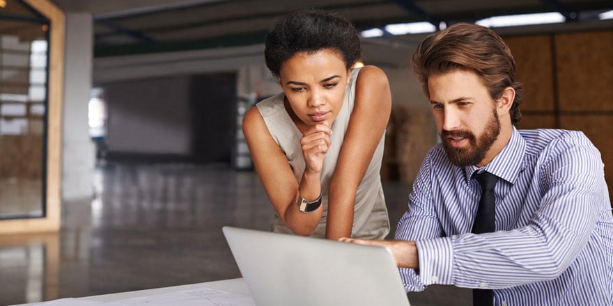 Two colleagues review the details of their company’s interest rate derivatives on a laptop