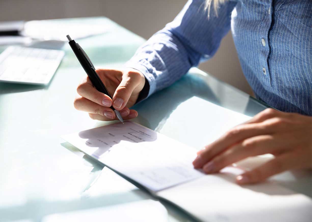 Close up of a business owner writing a check to open a new business checking account