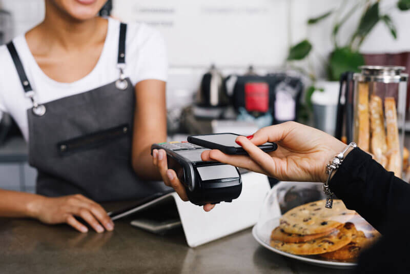A customer is using a phone to make a digital payment purchase at a coffee shop