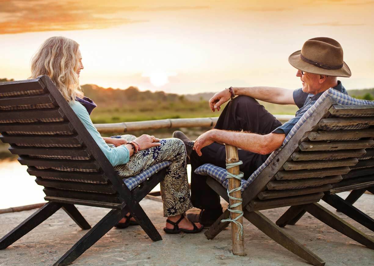 A man and women who are Diamond Savings clients are relaxing in deck chairs on the beach